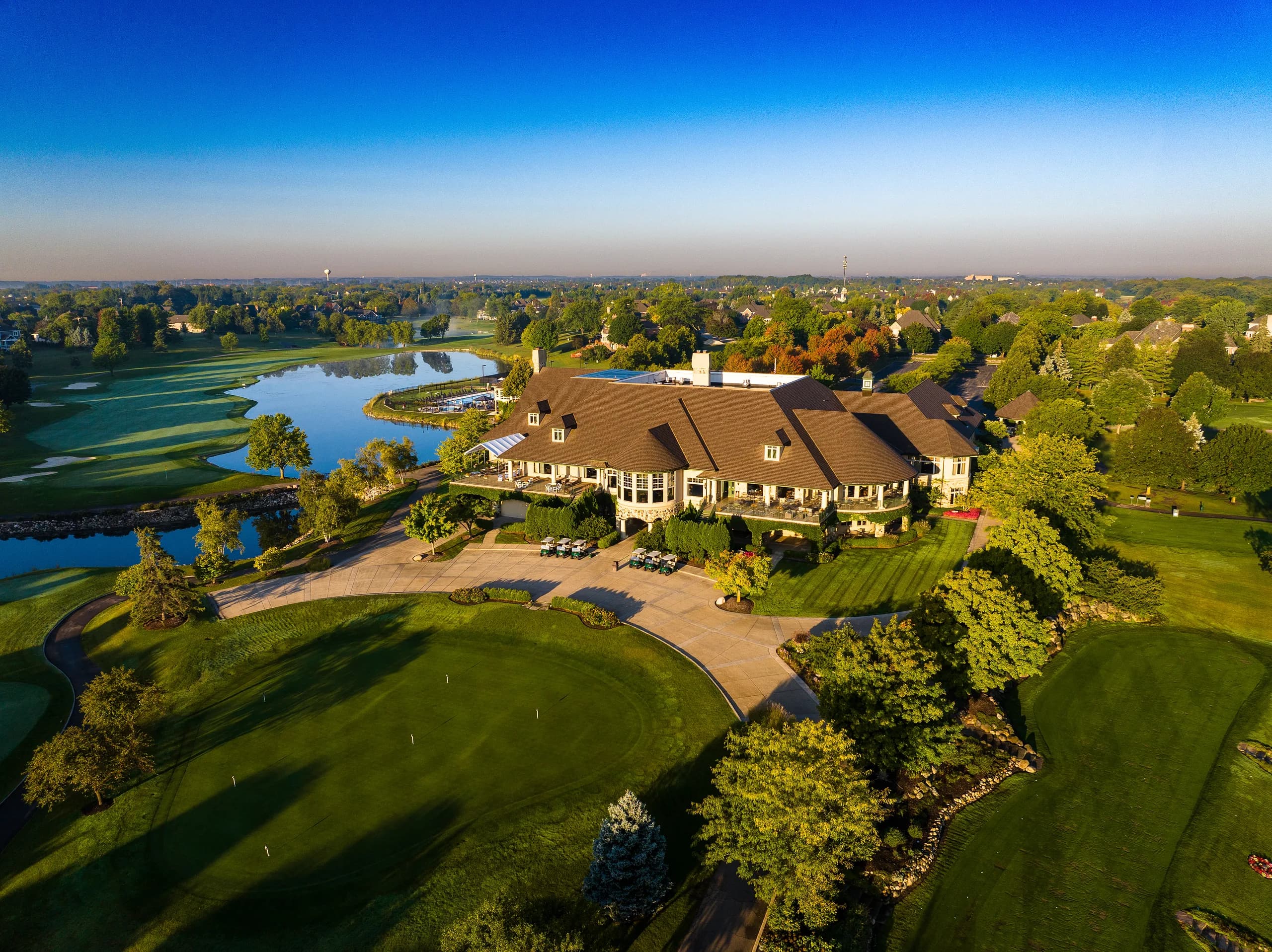 Grand clubhouse estate ringed by ponds and greens in early evening light